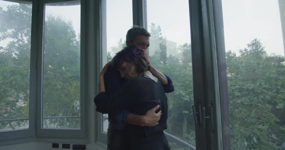 Couple hugs in front of windows