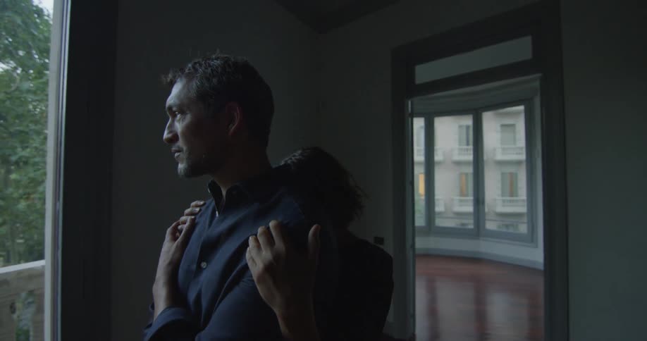 A woman hugging a man from behind in an empty house