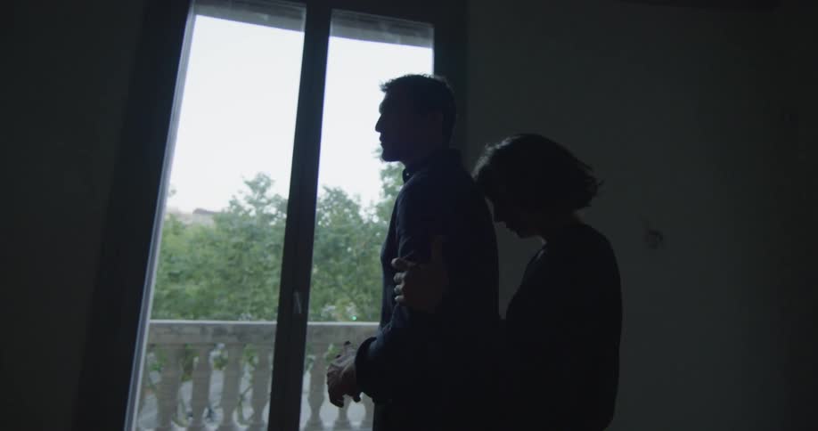 A woman embracing a woman from behind in a dark room
