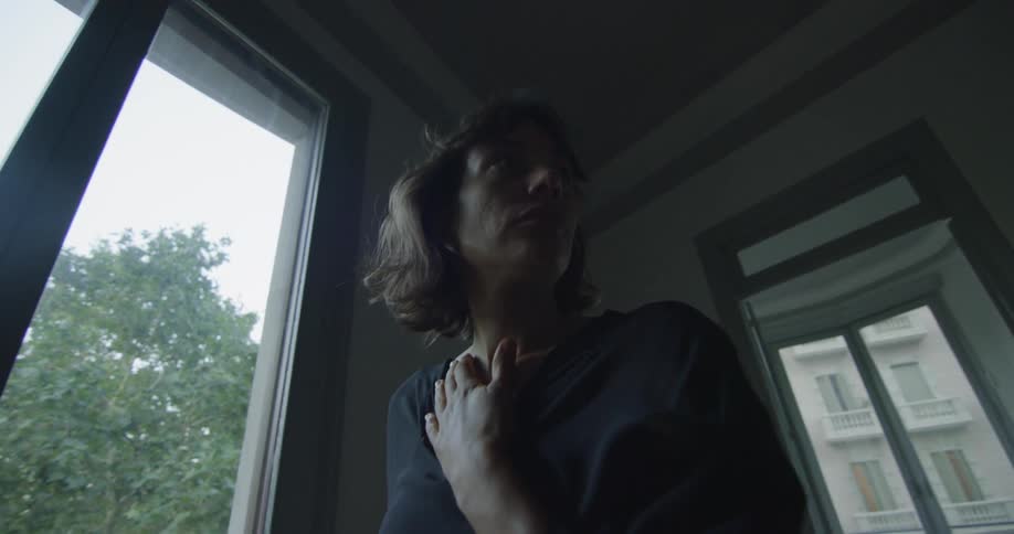 A woman grasping her neck and looking around
