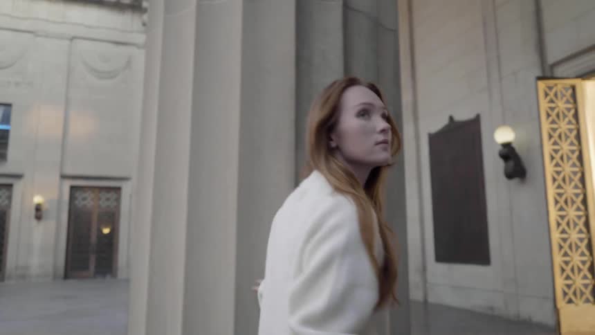 Girl walks around stone pillar in building