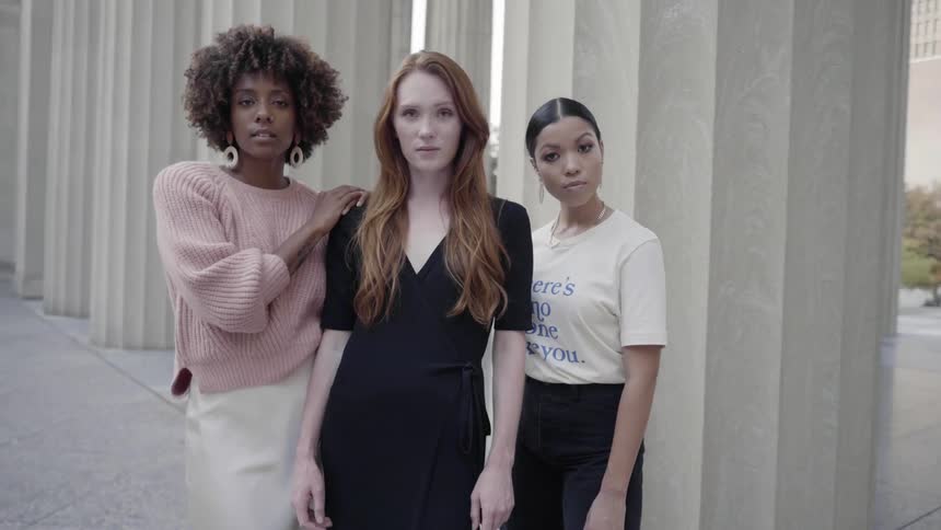 Three models posing in front of a building