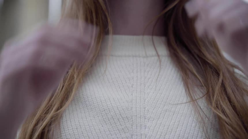 Woman who has pullover on throws her ginger hair back by day