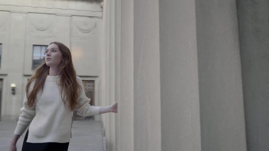 A woman is walking by architecture buildings