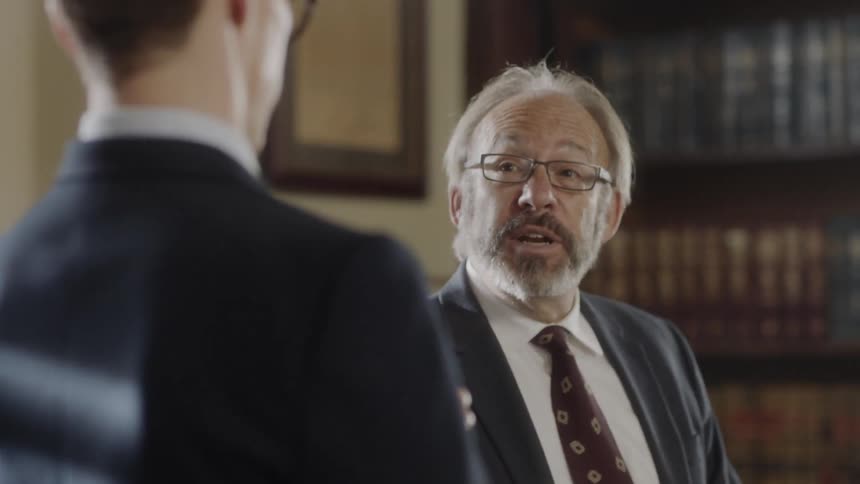 Two men talking in an office full of books