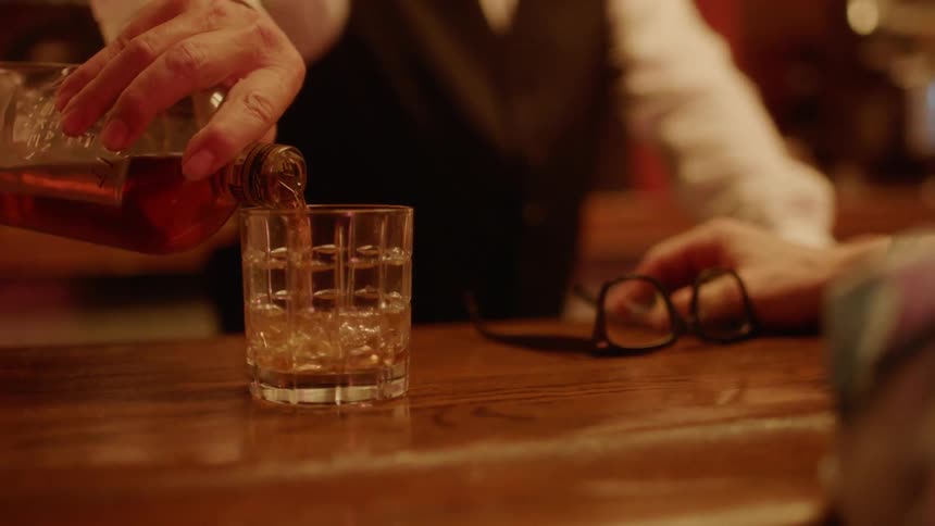 A man's drink is refilled after slamming his hand on the counter in a bar