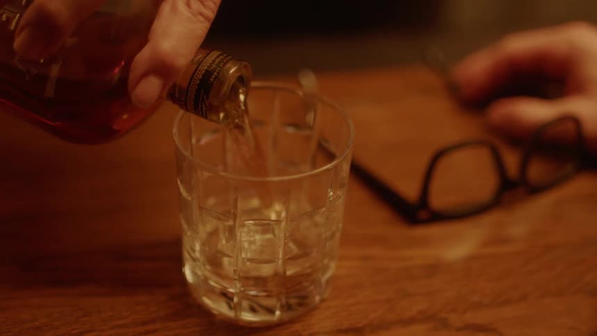A man slams his fist on a counter demanding more liquor in a bar