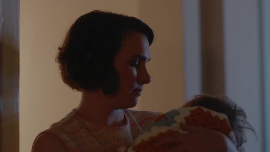 A mother rocks and soothes a baby wrapped in a blanket