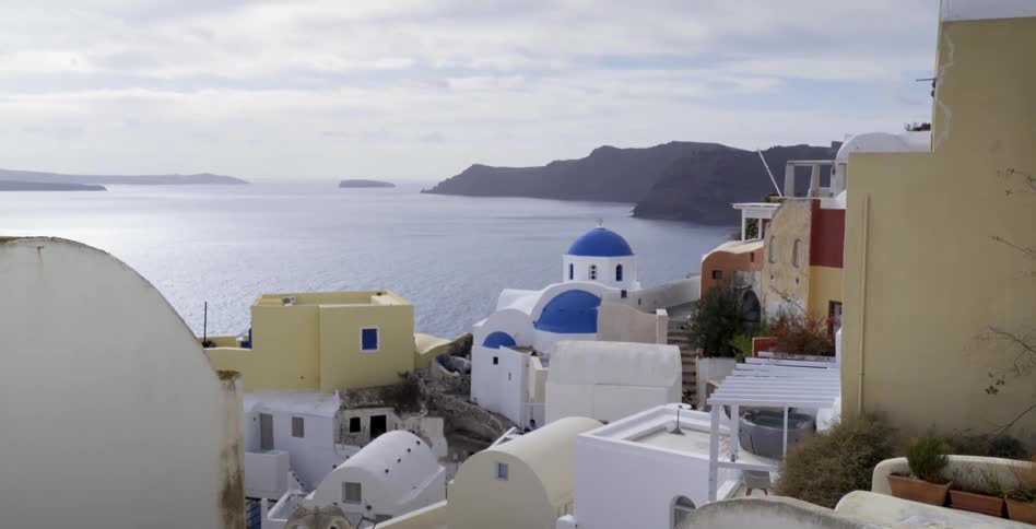 A town has many stone buildings on a hill by the shore
