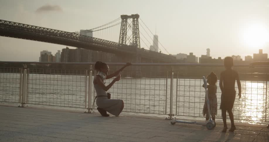 Children play next to a river while people walk by