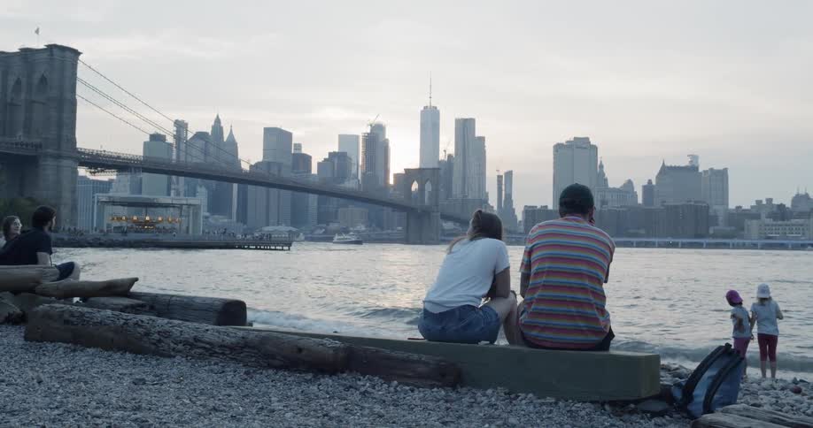A man woman and children sitting at a Brooklyn waterfront watching two girls play