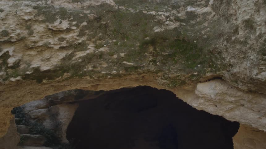 The camera pans down into a dark cave with steps carved out of it