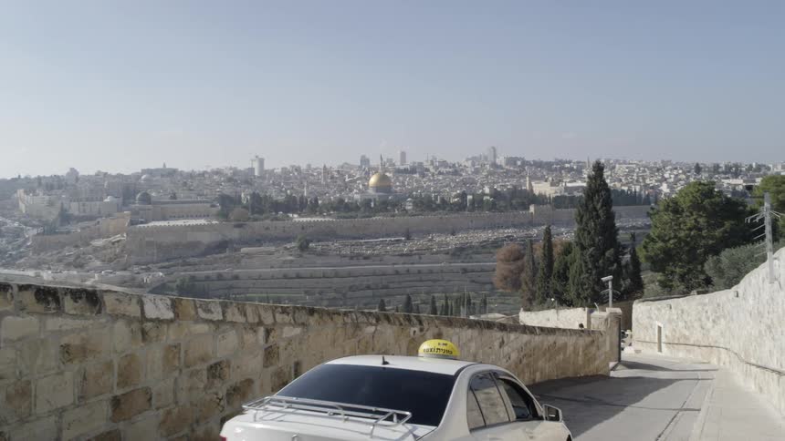 A taxi descending a road on a slope during the day