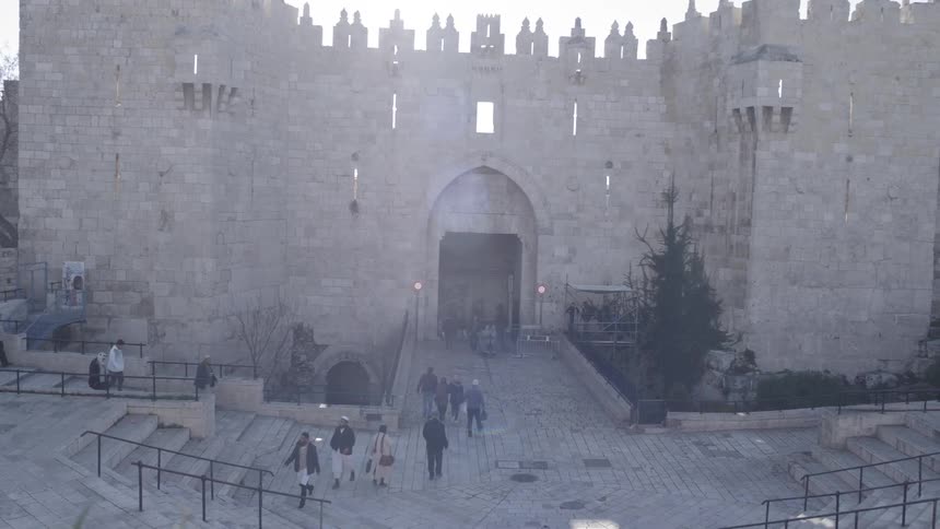People visit old medieval castle entering from its gate on a sunny day