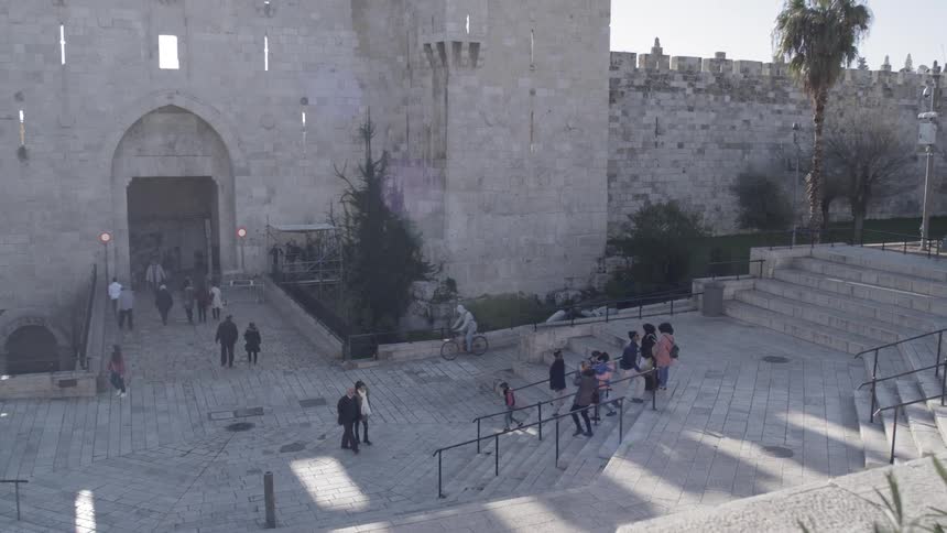 Pedestrians walk up and down stone steps in a city