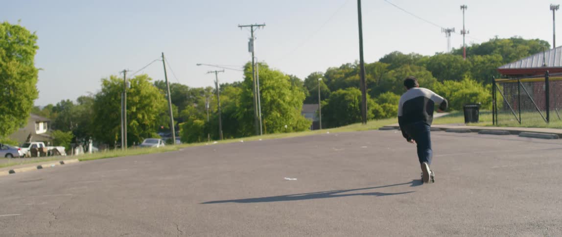 A man skateboarding an empty parking lot during the day