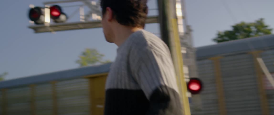 Man picks up skateboard near passing train
