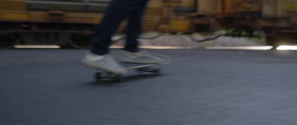Person on a skateboard rides towards a train then jumps off