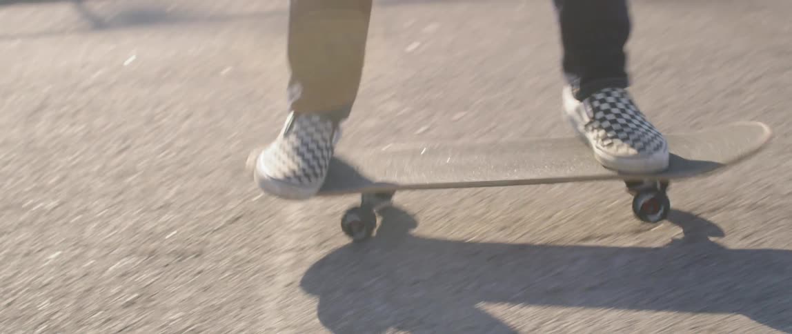 A teenager wearing checkered shoes does some quick turns on a skateboard