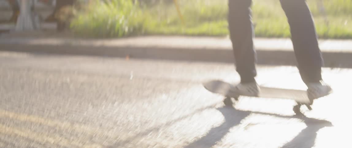 A man skateboards on a street turning around and heading towards a train car