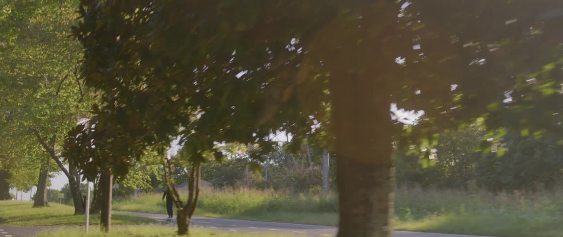 Man rides skateboard along sidewalk near road