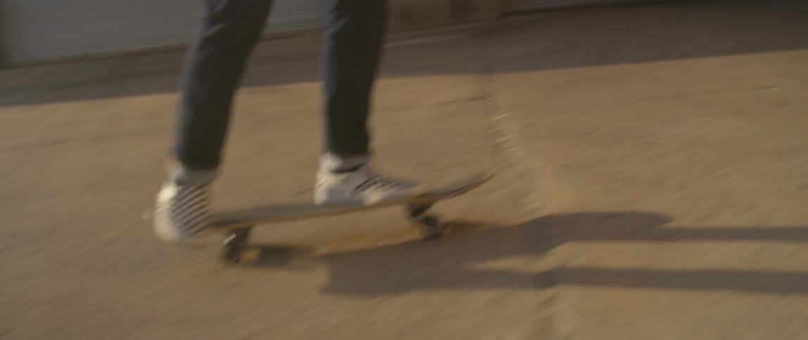 A person rides a skateboard in the sun
