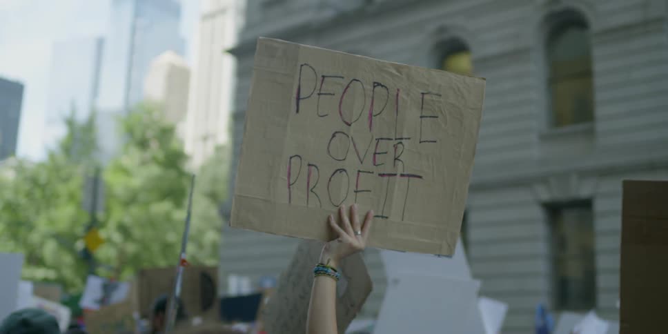 Protester hands holding up signs during a protest on a city street on a sunny day