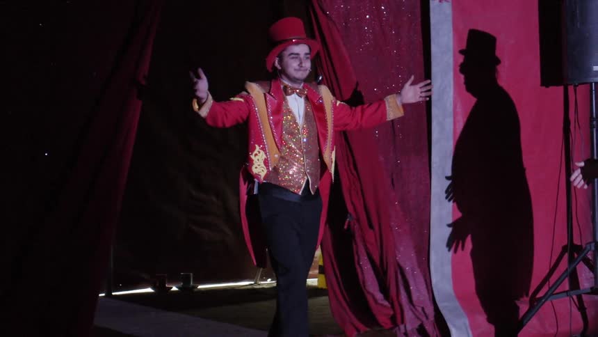 A performer comes through a curtain and walks towards a clown