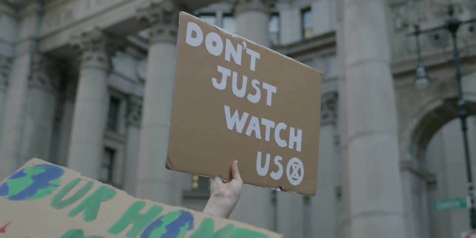 A protester holds a cardboard sign at a demonstration
