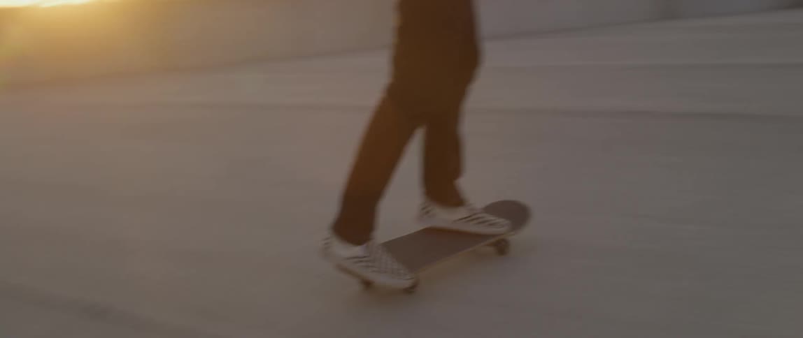 A man skateboarding in a rooftop parking lot at sunset
