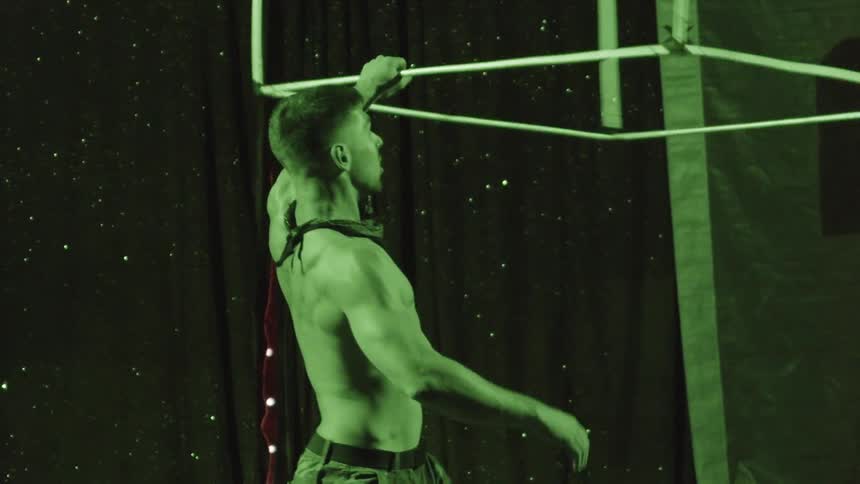 A performer spins and balances a large cube made from metal poles