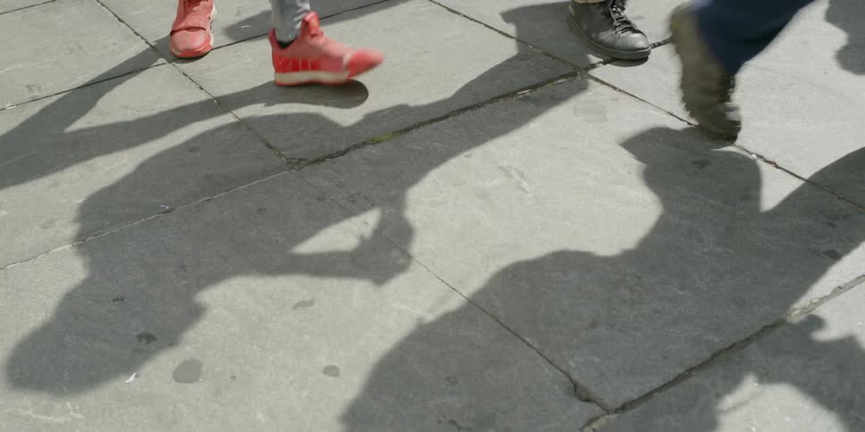 Feet of people walking along sidewalk