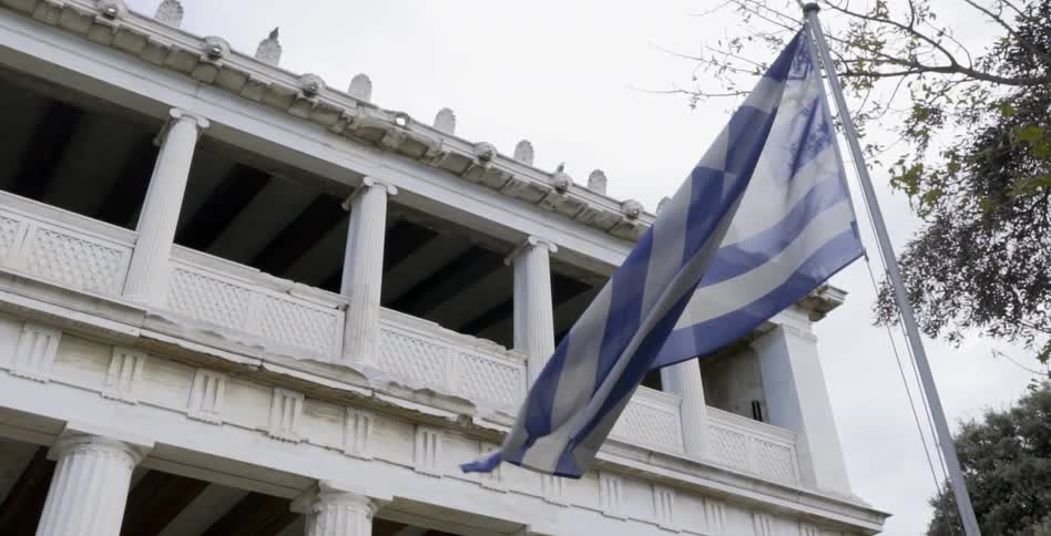 A flag waving in the breeze in front of a white building