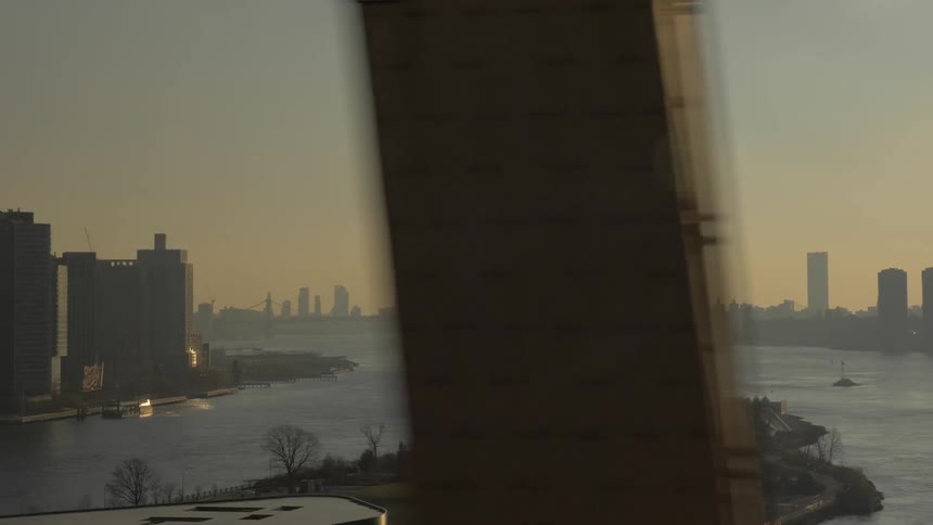 Passing the steel beams of a bridge looking out at the city skyline and harbor