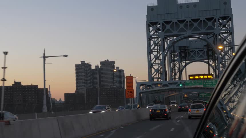 Cars drive over a city bridge at sunset