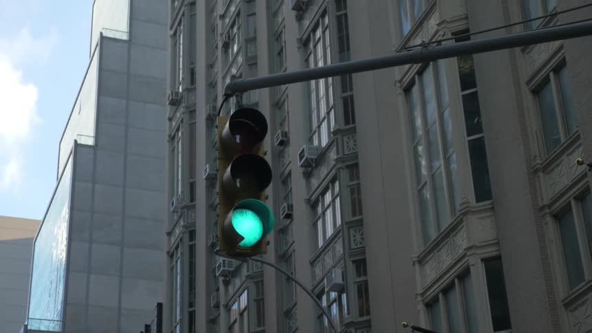 A car drives beneath a green traffic light in a city