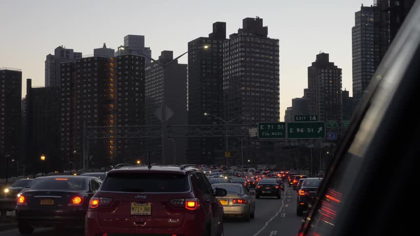 Many cars slowly driving along a busy downtown street