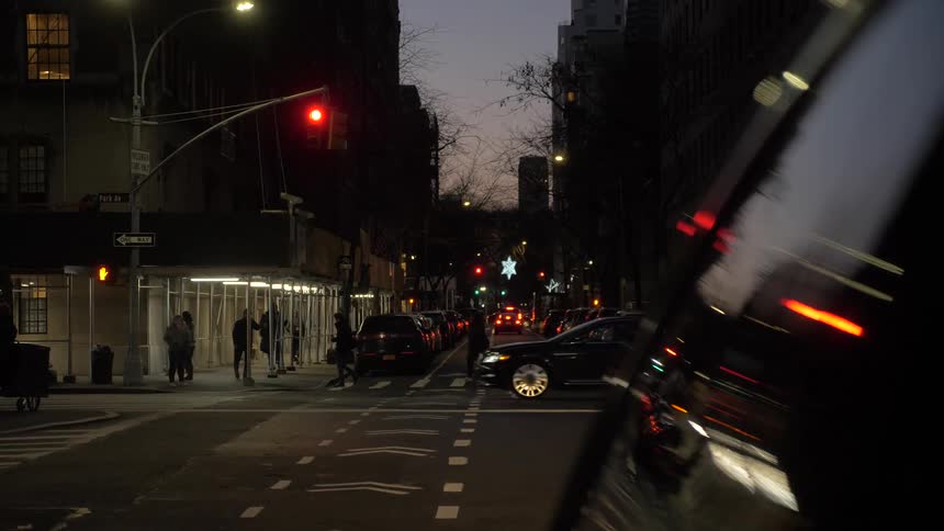 People walk across the crosswalk while cars drive by