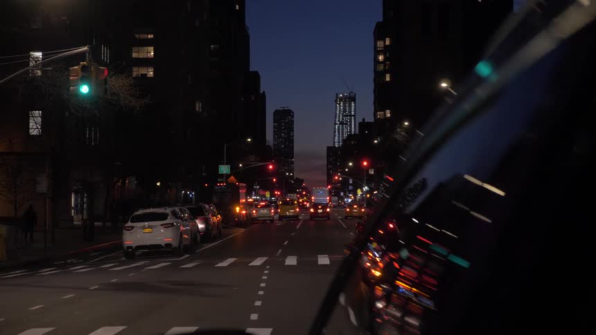 The camera looks down a busy street at night
