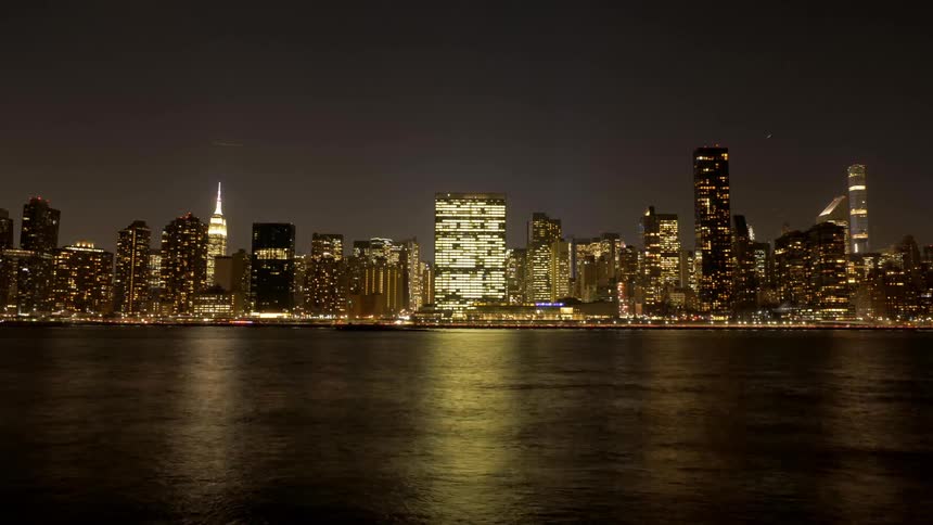 A city skyline at night and a busy river in the foreground