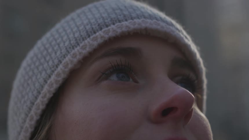 A woman stands in a city looking up and smiling