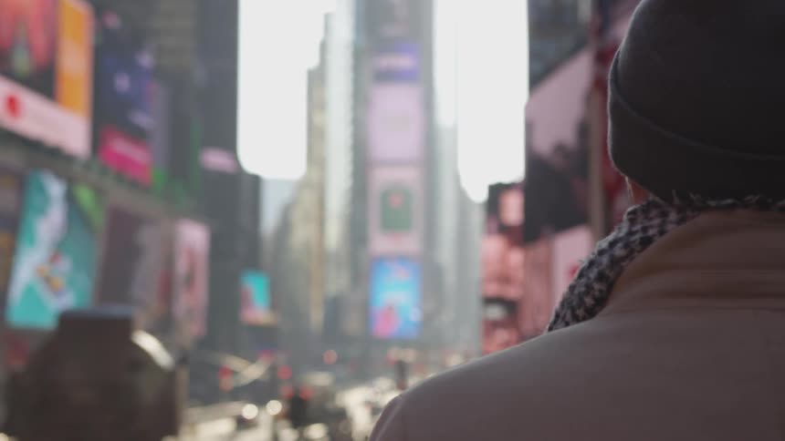 Back of many as he looks out at busy bright city before him