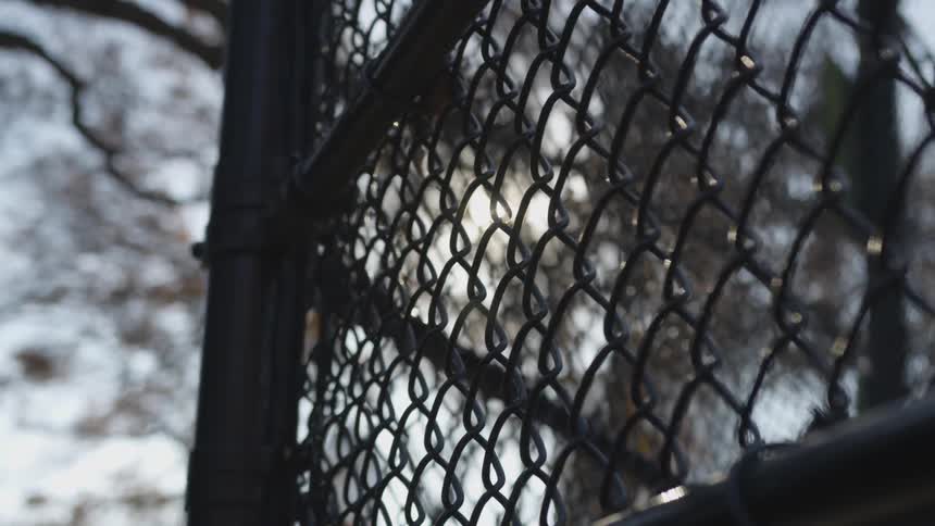 Chain link fence with sun shining through holes