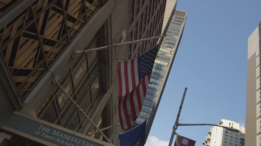 American flag on pole attached to city building flaps in the wind