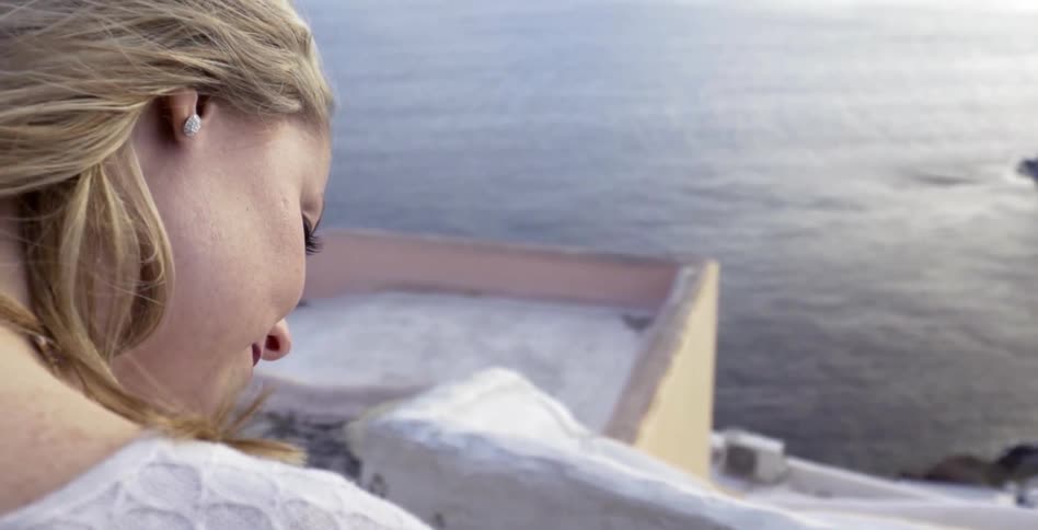 A young woman sitting on a rooftop overlooking the ocean