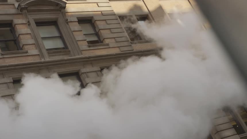 Thick smoke blows by huge building