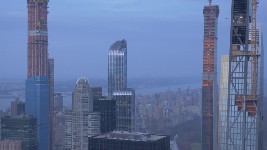 A city skyline at low sun with three skyscrapers under construction