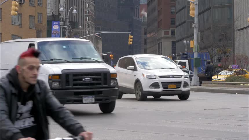 Cars and pedestrians travel on a busy city street