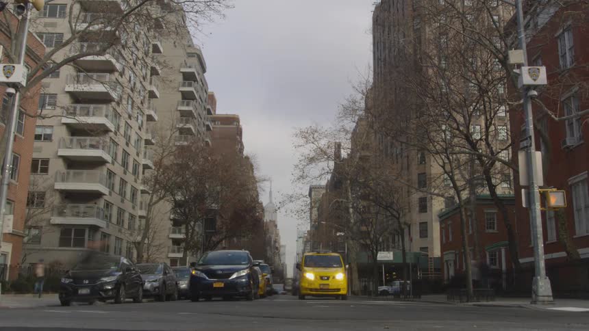 Cars and pedestrians travel in a city on a cloudy day