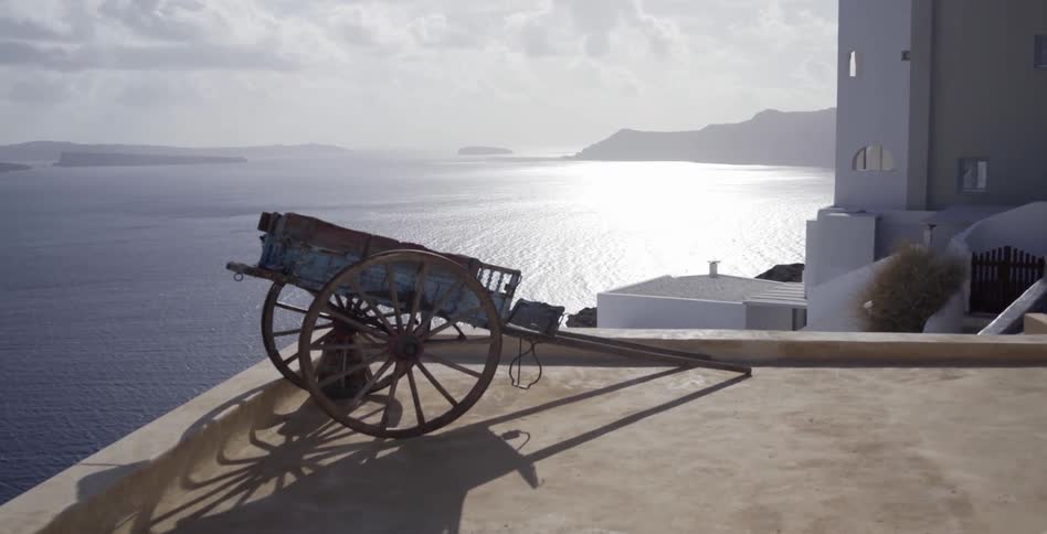 An old carriage sits at the ledge of a building on the shoreline